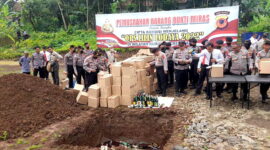 Anggota Polres Ciamis tengah melempar ribuan  botol miras kelubang tanah. (Doc Asajabar.com)