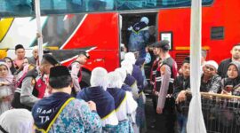 Calon jemaah haji berangkat menuju bus.