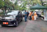 Kendaraan plat merah tengah diperiksa uji emisi oleh petugas.