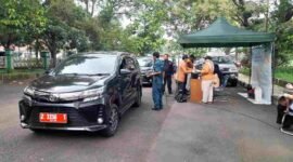 Kendaraan plat merah tengah diperiksa uji emisi oleh petugas.