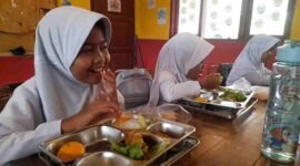 Siswi SDN 1 Kutawaringin tengah menyantap MBG dengan wajah gembira.