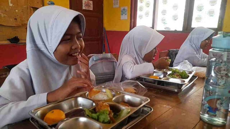 Siswi SDN 1 Kutawaringin tengah menyantap MBG dengan wajah gembira.