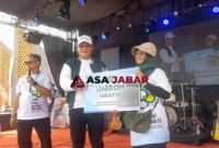 Kepala Kanwil Kemenag Jawa Barat, H. Dudu Rohman tengah memberikan Hadiah Umroh kepada pemenang undian gerak jalan sehat harmoni beragama.