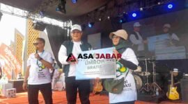 Kepala Kanwil Kemenag Jawa Barat, H. Dudu Rohman tengah memberikan Hadiah Umroh kepada pemenang undian gerak jalan sehat harmoni beragama.