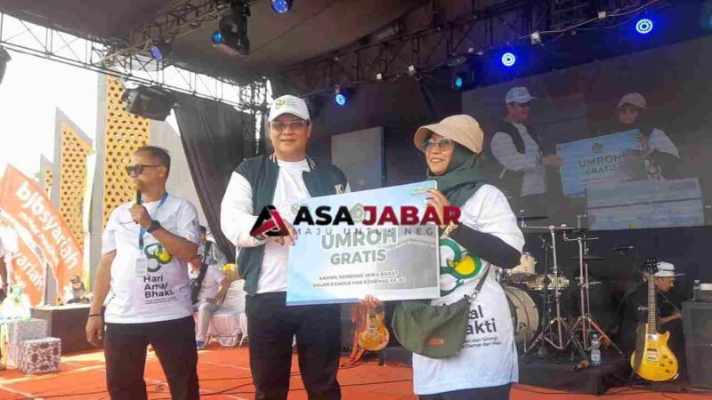 Kepala Kanwil Kemenag Jawa Barat, H. Dudu Rohman tengah memberikan Hadiah Umroh kepada pemenang undian gerak jalan sehat harmoni beragama.