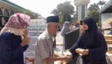 Panitia membagikan makanan gratis kepada jemaah usai Salat Jumat dalam program