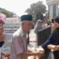 Panitia membagikan makanan gratis kepada jemaah usai Salat Jumat dalam program 